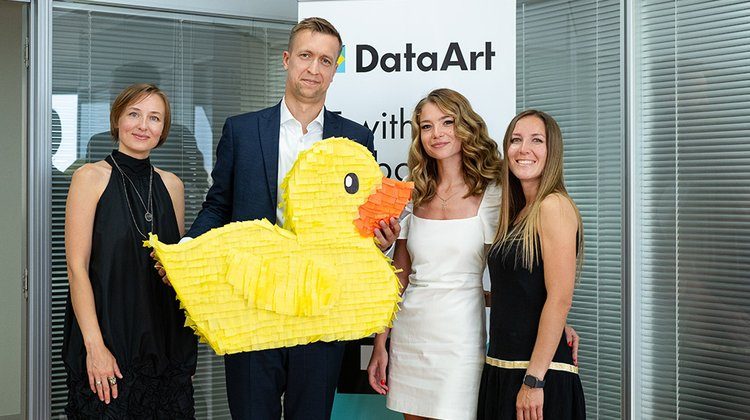 Data Αrt managing director with three other women employees, holding a yello duck, the company's logo.