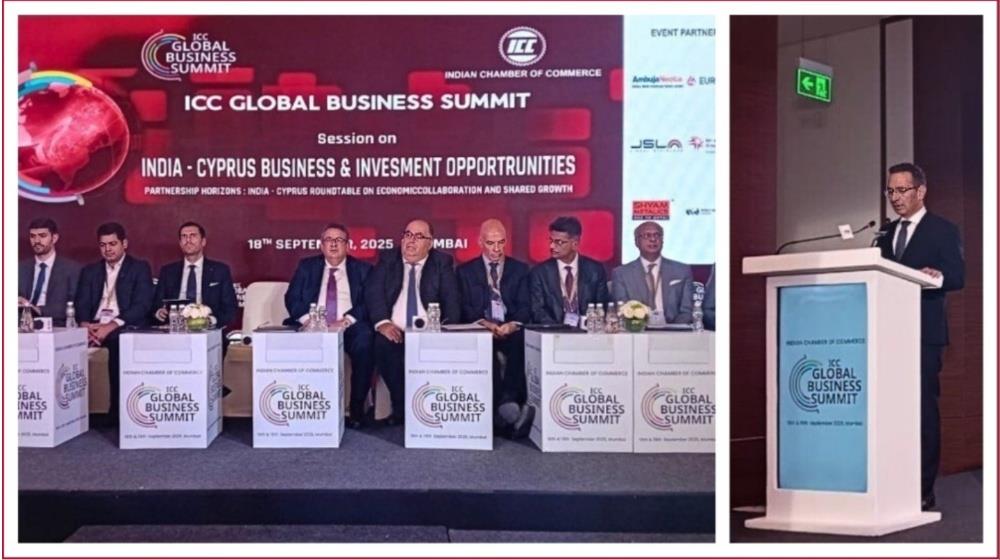 Officials sit on stage during the ICC Global Business Summit while the Cyprus Research Minister addresses Indian business representatives.